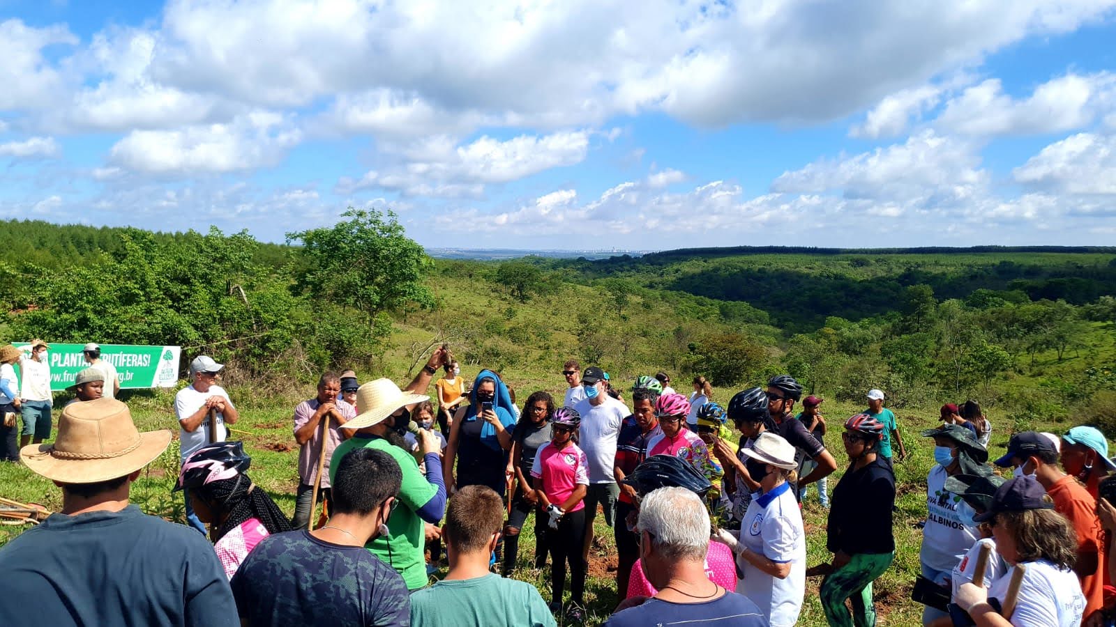 Comunidade reunida no plantio, com a faixa do Fruto Urbano ao fundo