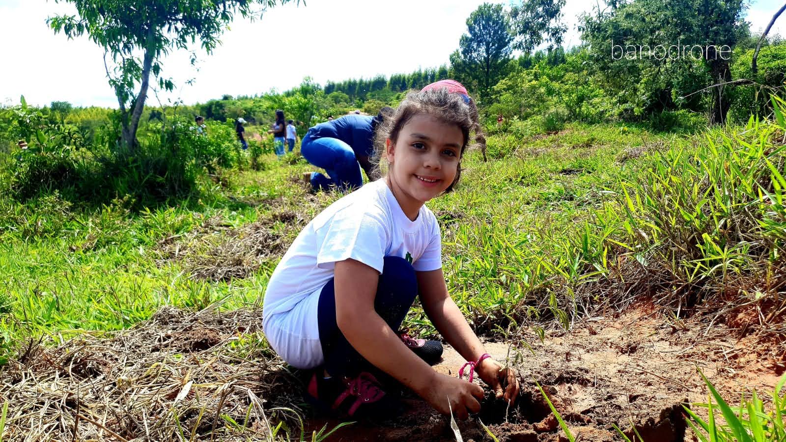 Criança participando do plantio de uma muda
