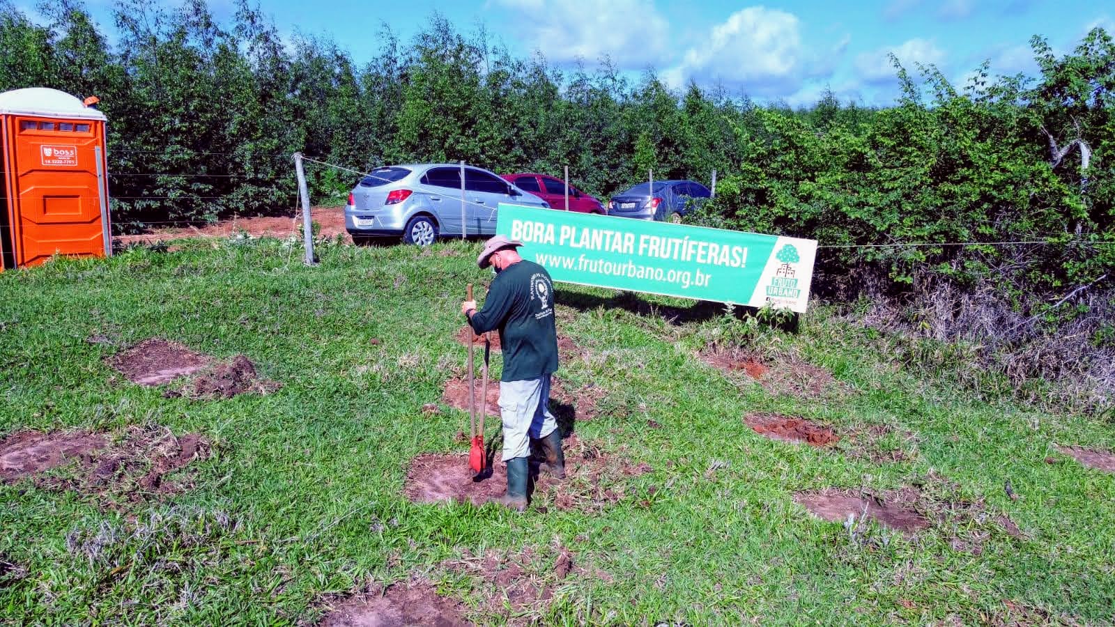 Participante junto a uma muda e à faixa do Fruto Urbano